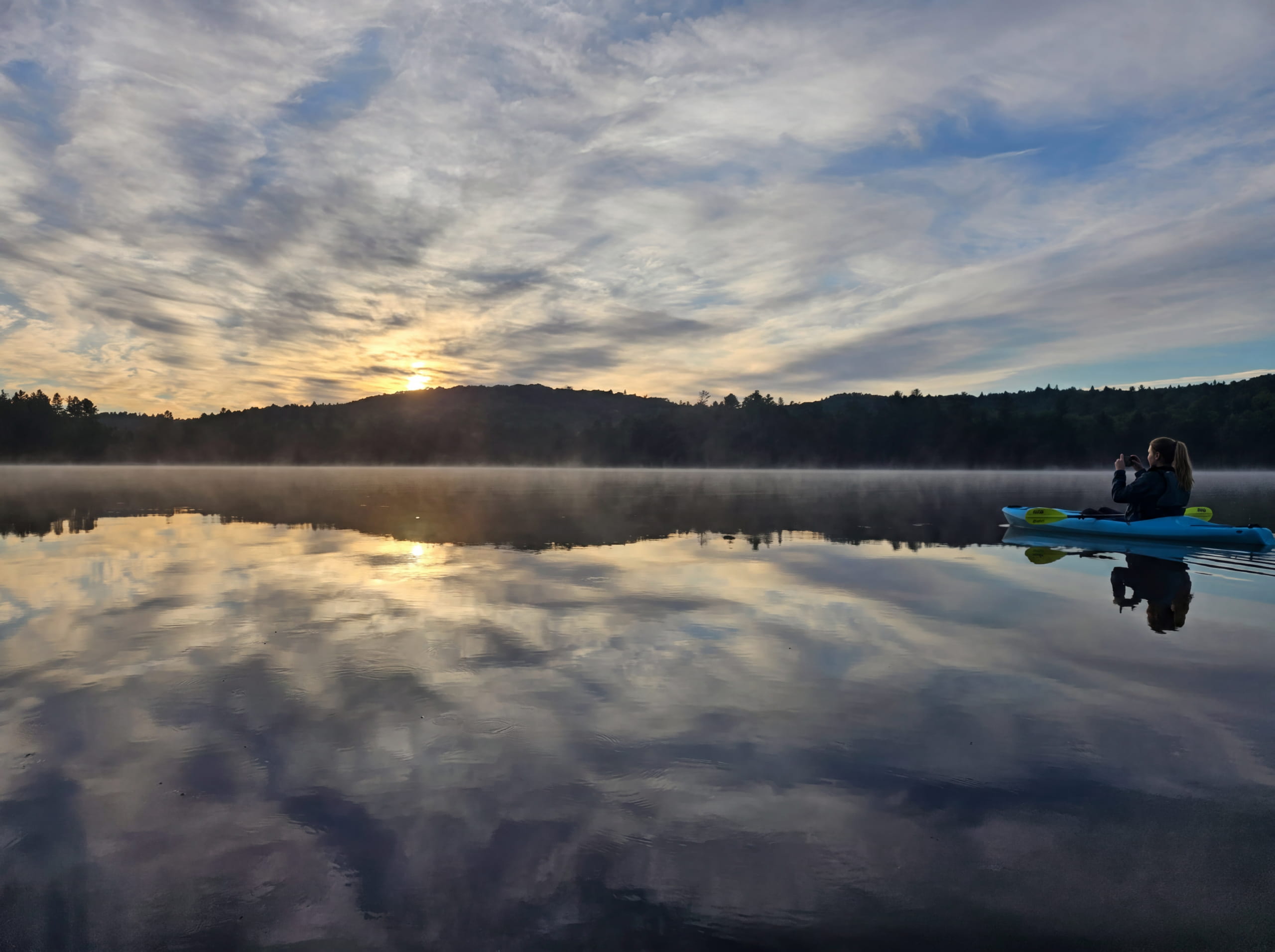 Kayaker on a Vermont pond at sunrise with mist on the water